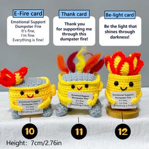 May include: Three handmade crochet figures in the shape of yellow buckets with smiling faces and gray legs. Each holds a sign that reads "Emotional Support Dumpster Fire." The figures have red and yellow flame-like accents. Height: 2.76 inches.