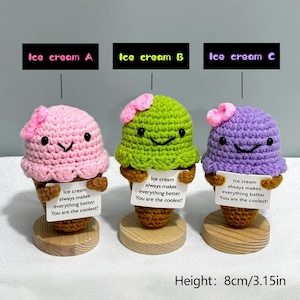 May include: Three crocheted ice cream cone figurines in pink, green, and purple. Each has a smiling face, a small flower, and a sign that reads "Ice cream always makes everything better. You are the coolest!" The height is 3.15 inches.