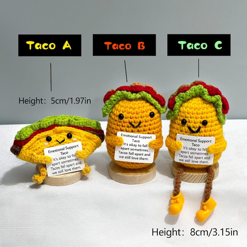 May include: Three crocheted taco toys, labeled Taco A, B, and C. Taco A is flat, while B and C are upright. Each has a smiling face and holds a sign that reads "Emotional Support Taco." Taco C is 8cm/3.15in tall.