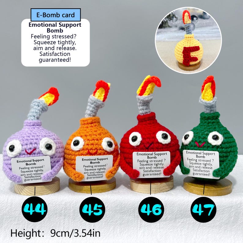 May include: Four handmade crochet "Emotional Support Bombs" in purple, orange, red, and green, each with a smiling face and a flame-like top. Each bomb is approximately 3.54 inches tall and includes a small wooden base.