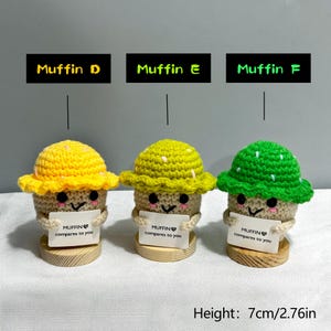 May include: Three crocheted muffin figures with smiling faces, each holding a sign that reads "MUFFIN compares to you." The muffins have yellow, green, and lime green hats. The height is 2.76 inches.