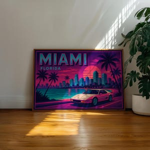 May include: A framed art print featuring a retro Miami, Florida design. The artwork showcases a pink sports car on a road, palm trees, a cityscape, and the text "MIAMI FLORIDA" in teal and pink hues.