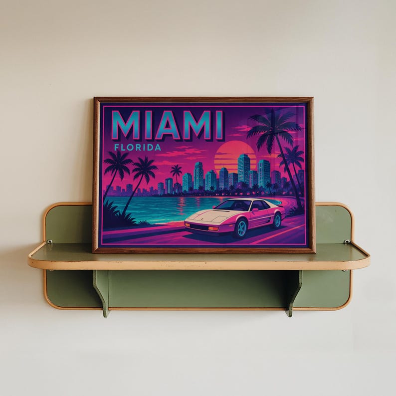 May include: Framed art print featuring a retro Miami, Florida design. The artwork showcases a pink sports car on a coastal road, palm trees, and a city skyline under a vibrant sunset. The word "MIAMI" is prominently displayed.