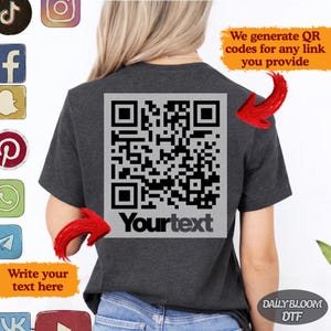 May include: Dark gray t-shirt with a large QR code graphic on the back. The QR code is in a gray rectangle with the text "Yourtext" below it. The shirt also has the text "We generate QR codes for any link you provide" and "Write your text here".