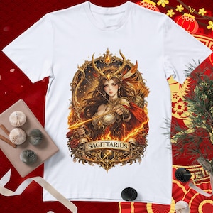 May include: White t-shirt featuring a detailed illustration of a Sagittarius woman with a bow and arrow, surrounded by flames and roses. The design includes the word "SAGITTARIUS" and the Sagittarius symbol.