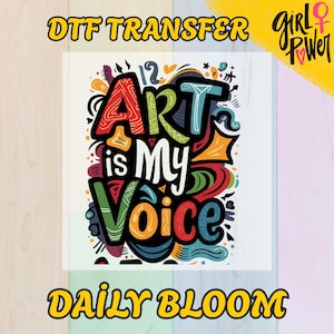 May include: A colorful graphic with the words "ART is MY VOICE" in a whimsical font. The design includes various shapes and patterns in red, blue, green, and orange. The text "DTF TRANSFER" and "DAILY BLOOM" are also present.