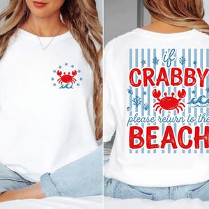 May include: White sweatshirt with a red crab graphic and the text "if CRABBY please return to the BEACH" on the back. The front features a smaller crab design with stars and waves. A casual, beach-themed apparel item.
