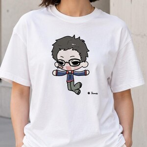May include: A white short-sleeved t-shirt featuring a centered graphic of a cartoon character with dark hair and glasses, wearing a blue jacket and gray pants. The character is depicted in a chibi style with the text James printed near the bottom right.