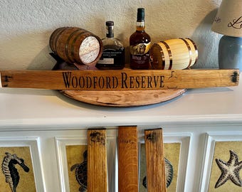 May include: A display featuring a wooden sign with "Woodford Reserve" text, small wooden barrels, and liquor bottles. The sign is mounted above a shelf with decorative wooden planks. The overall theme is related to whiskey.