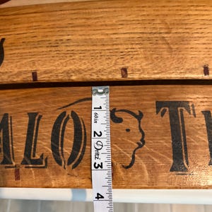 May include: Wooden sign with the words "Buffalo Trail" in black lettering and a buffalo head silhouette. The sign is approximately 2 inches wide, as measured by a tape measure.