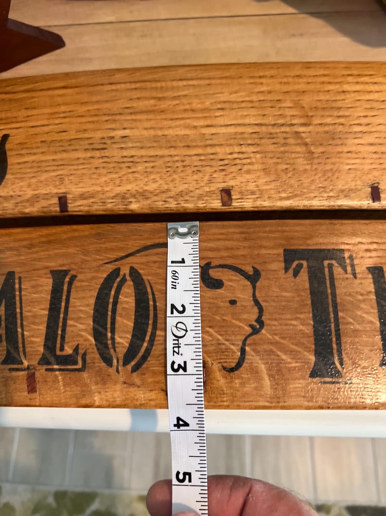 May include: Wooden sign with the words "Buffalo Trail" in black lettering and a buffalo head silhouette. The sign is approximately 2 inches wide, as measured by a tape measure.