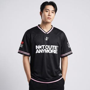 May include: Black jersey with pink trim and the text "NXT CUTE ANYMORE" in white. The jersey has a V-neck and short sleeves. A red heart and the letter "E" are on the left sleeve. The right sleeve has the letters "I M".