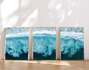 Può includere: Tre stampe artistiche incorniciate raffiguranti viste aeree di onde oceaniche. L'opera d'arte presenta sfumature di blu e bianco, catturando il movimento e la consistenza dell'acqua. Le cornici hanno una finitura in legno chiaro, aggiungendo un tocco naturale.