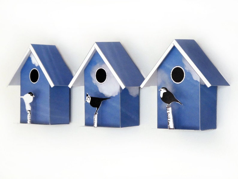 May include: Three blue birdhouses with white trim and a white cloud design. Each birdhouse has a round opening and a small bird perched on a branch in front of it.