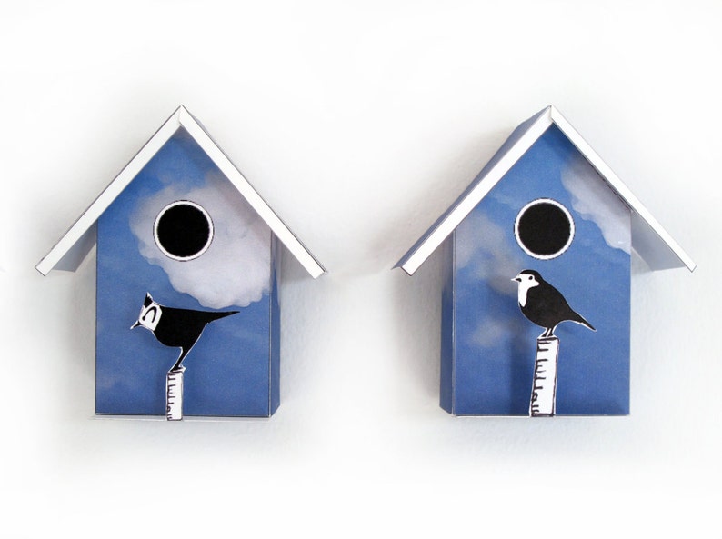 May include: Two blue birdhouses with white trim and a white cloud design. Each birdhouse has a black bird perched on a white pole.