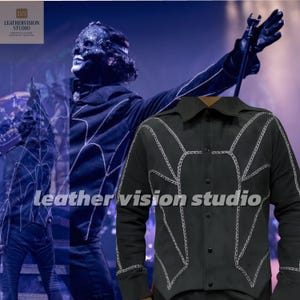 May include: Black button-up shirt with white stitching in a web-like pattern. The shirt has a collar and long sleeves. The image also features a blurred background with a person wearing a black outfit and the text "leather vision studio".