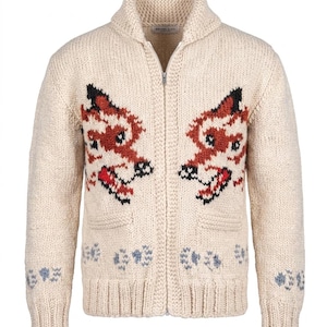 Puede incluir: Cárdigan crema con cremallera y cuello chal. El suéter presenta un diseño detallado de zorro en rojo, negro y blanco en la parte delantera. Tiene dos bolsillos delanteros y un patrón floral decorativo en la parte inferior. La marca "BRUUN & CO" es visible.