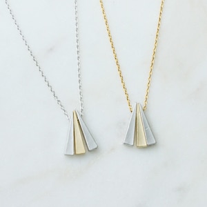 May include: Two delicate necklaces with a simple chain design. Each necklace features a pendant made of two overlapping triangles, one gold and one silver.
