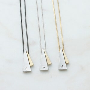 May include: Three silver triangle necklaces with gold accents. Each necklace features a different letter: A, C, and E. The necklaces are on a white background.