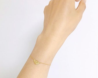 May include: A delicate gold chain bracelet with a small, detailed leaf charm. The bracelet is shown on a person's wrist.