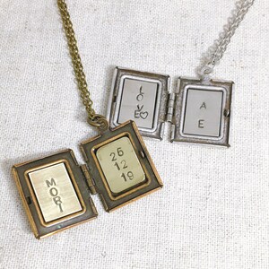 May include: Two gold locket necklaces with engraved messages. One locket has the words "MORI" and "26 12 19" engraved on it. The other locket has the words "LOVE" and "AE" engraved on it.