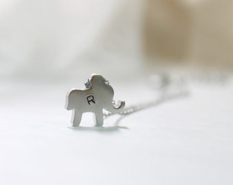 May include: A silver elephant charm necklace with the letter "R" engraved on the side.