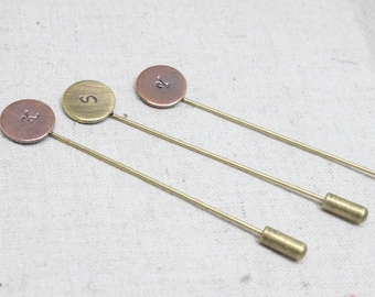May include: Three gold-toned tie tacks with round metal tops. The tops are engraved with the letters "K", "S", and "D".