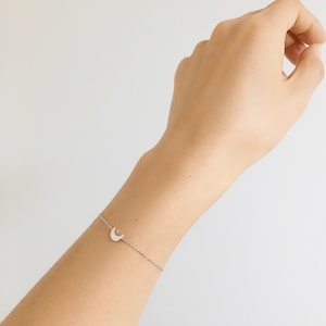 May include: A silver chain bracelet with a crescent moon charm.