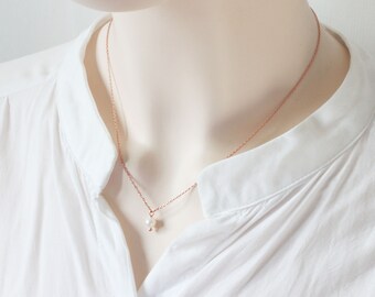 May include: A delicate rose gold chain necklace with a single white pearl pendant.
