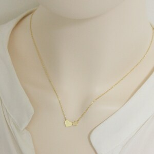 May include: A gold chain necklace with two small heart charms.