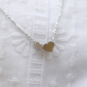 May include: A silver necklace with two small, connected heart charms.