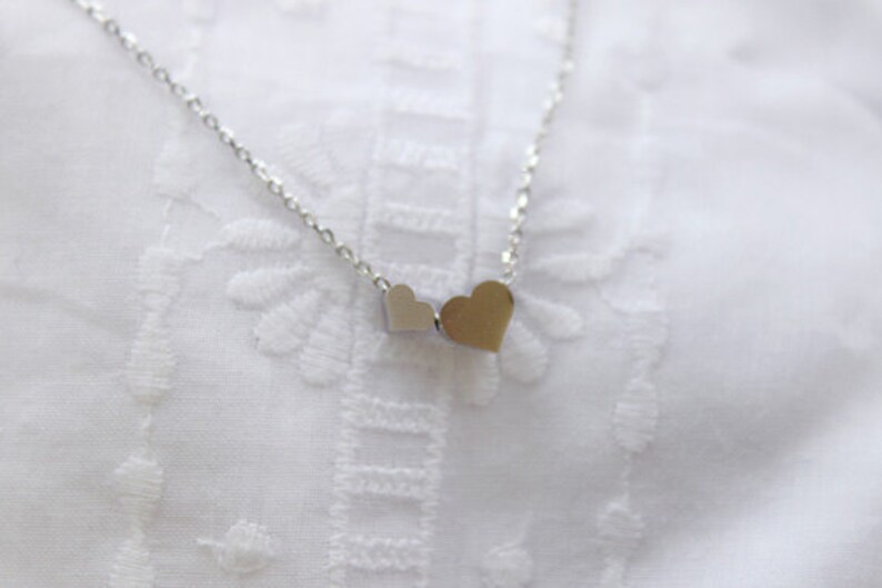 May include: A silver necklace with two small, connected heart charms.