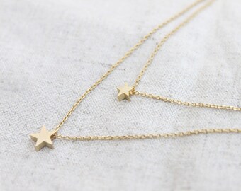 May include: A gold chain necklace with two star pendants. The necklace is layered and has a delicate chain.