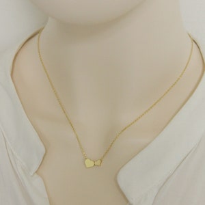 May include: A gold chain necklace with two small heart pendants.