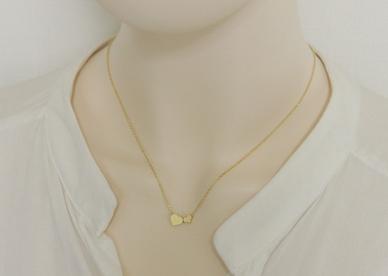 May include: A gold chain necklace with two small heart pendants.