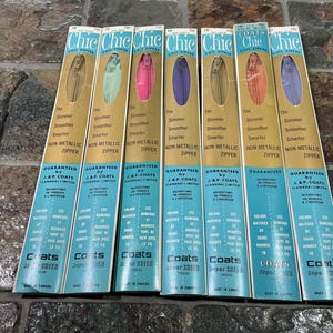 May include: A collection of seven vintage "Chic" coil zippers in various colors, including gold, pink, purple, and blue. Each package features text that reads "The Slimmer, Smoother, Smarter Non Metallic Zipper."
