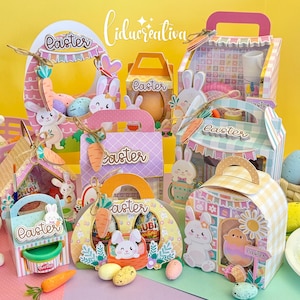 Puede incluir: Una colección de cajas y recipientes de regalo con temática de Pascua. Las cajas presentan decoraciones de conejos y zanahorias, con la palabra "Easter". Las cajas son de varias formas y tamaños, con colores pastel y elementos decorativos.