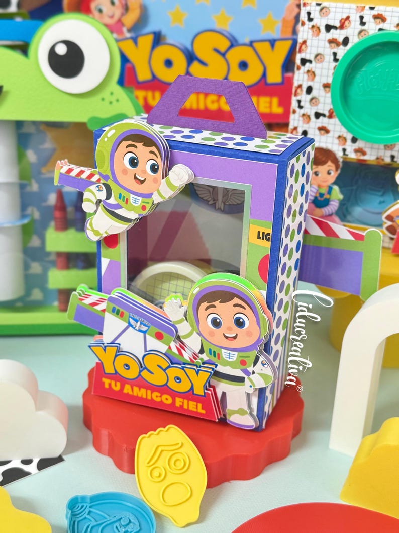 May include: A rectangular paper gift box featuring Buzz Lightyear character cutouts, a purple handle, and blue and white polka dot side panels. The front displays the text Yo Soy Tu Amigo Fiel with a clear window showing internal contents.