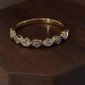 Aliança de casamento com diamante em formato de pera curva, anel ondulado em ouro, anéis sobrepostos, aliança de noivado delicada com contorno.