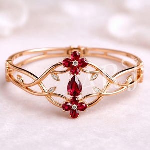 Könnte beinhalten: Ein aufklappbarer Armreif aus Roségold mit einem zentralen Design aus zwei vierblättrigen roten Edelsteinblüten und einem einzelnen birnenförmigen roten Edelstein. Das Metallband ist mit kleinen, klaren Pavé-gefassten Steinen verziert.