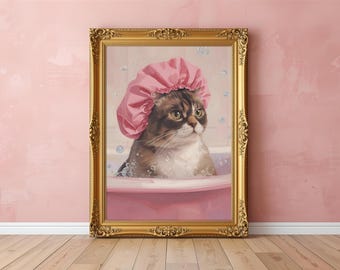 May include: A framed print of a cat wearing a pink shower cap, sitting in a pink bathtub with bubbles. The artwork is in a gold ornate frame, leaning against a pink wall and wooden floor.