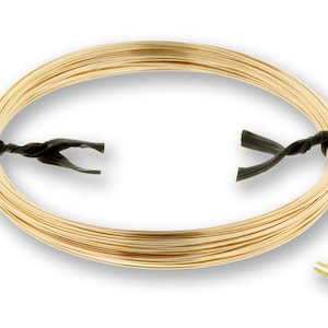May include: A coil of gold-colored round wire, secured with black ties. The wire is tightly wound, forming an oval shape. A small sample of the wire with the word "Round" is in the lower right corner.