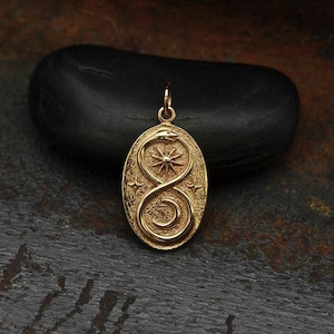 May include: Gold pendant featuring a snake curled into the shape of an infinity symbol, with a sun and stars in the background.