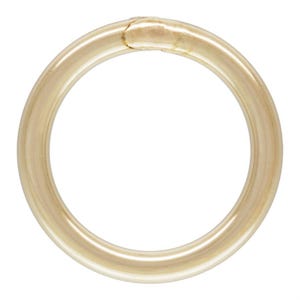 May include: A gold-colored, circular ring with a slightly textured surface. The ring appears to be made of metal and has a visible seam where the ends meet. The overall design is simple and elegant.