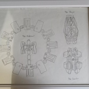 May include: Framed pencil sketch of a spacecraft design, featuring detailed diagrams labeled "The Endurance," "The Ranger," and "The Lander." The artwork is encased in a white frame, showcasing the technical drawings.