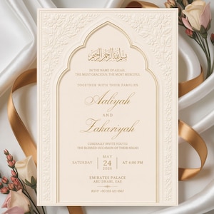 May include: Ivory wedding invitation with gold accents and floral embossed details. The invitation includes the names Aaliyah and Zakariyah, along with the date, time, and location of the Nikah ceremony. The text is in English and Arabic.