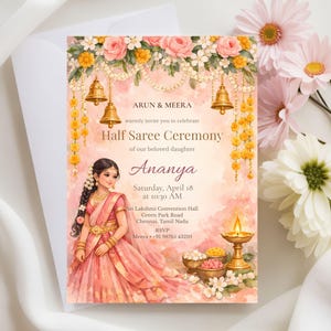May include: A watercolor invitation for a Half Saree Ceremony, featuring a young woman in a pink saree. The invitation includes text with the names Arun & Meera, the daughter's name Ananya, and event details. Floral and bell decorations adorn the top.