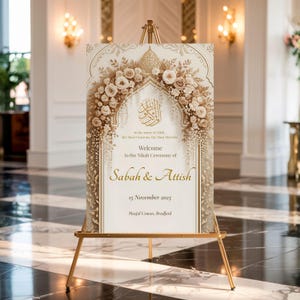 Elegant Nikah welcome sign with gold floral arch displayed on a gold stand inside a luxury wedding hall.