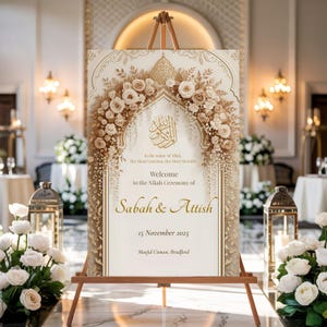 Elegant gold floral Nikah welcome sign on wooden easel in a classic wedding hall with lanterns and flowers.