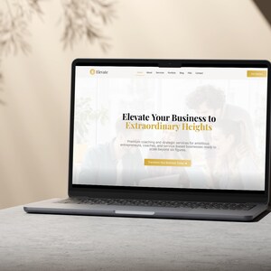 Pu&ograve; includere: Un laptop argentato che mostra un sito web con il testo "Elevate Your Business to Extraordinary Heights". Il sito web promuove servizi di coaching e strategici. Il laptop &egrave; su una superficie grigio chiaro con uno sfondo neutro.